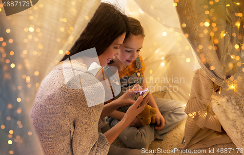 Image of happy family with smartphone in kids tent at home