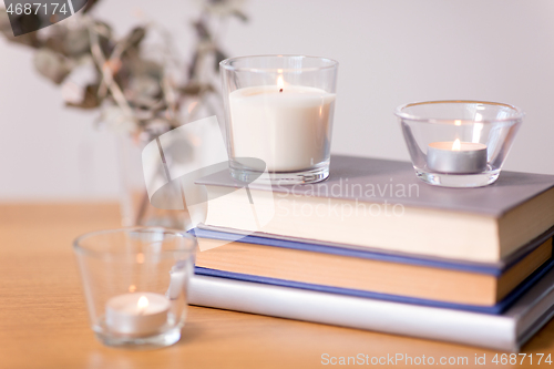 Image of fragrance candles burning and books on table