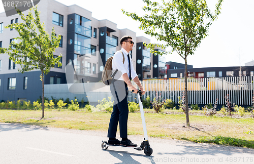 Image of businessman with backpack riding electric scooter