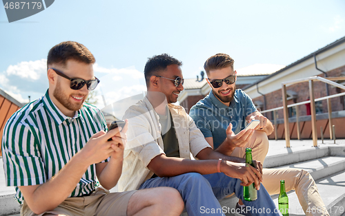 Image of men with smartphones drinking beer on street