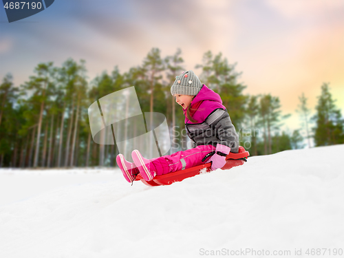 Image of happy little girl sliding down on sled in winter