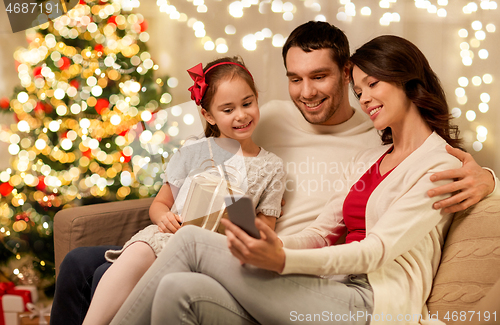 Image of family with smartphone at home on christmas