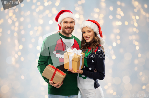 Image of happy couple in sweaters with christmas gifts