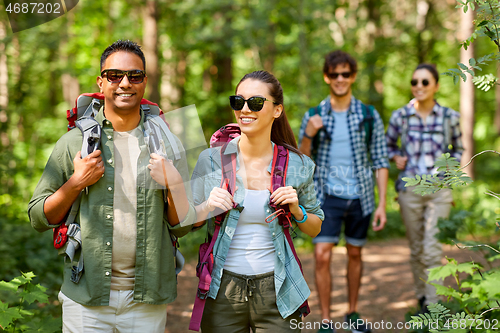 Image of group of friends with backpacks hiking in forest