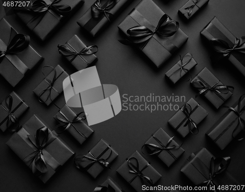 Image of Arranged Gifts boxes wrapped in black paper with black ribbon on black background. Christmas concept