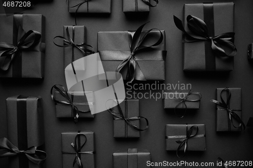 Image of Dark Christmas theme. Square boxed gifts wrapped in black paper and ribbon arranged on black