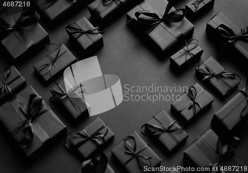 Image of Arranged Gifts boxes wrapped in black paper with black ribbon on black background. Christmas concept