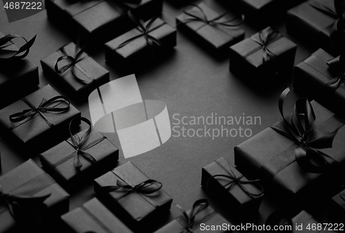 Image of Arranged Gifts boxes wrapped in black paper with black ribbon on black background. Christmas concept