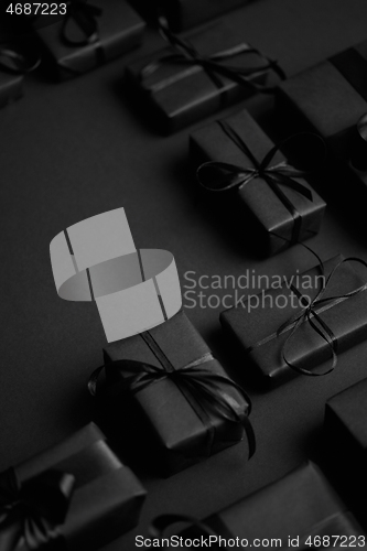 Image of Arranged Gifts boxes wrapped in black paper with black ribbon on black background. Christmas concept