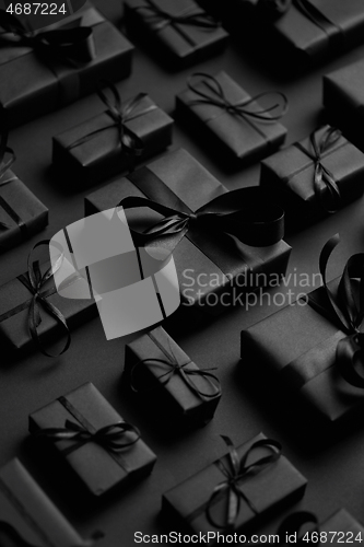 Image of Dark Christmas theme. Square boxed gifts wrapped in black paper and ribbon arranged on black