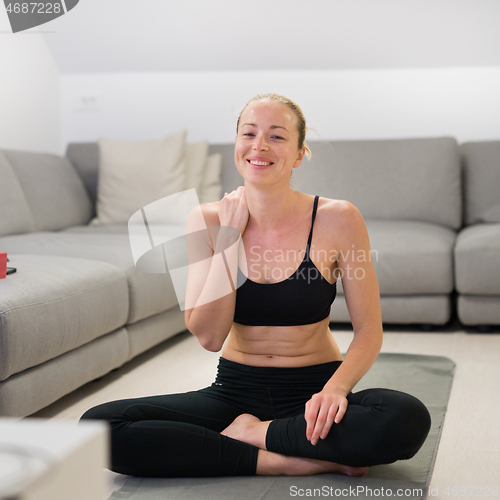 Image of Beautiful blonde woman doing home workout indoors. Woman practice yoga at home. Fit girl using workout tutorials for healthy active lifestyle. Woman using quarantine for home workouts.