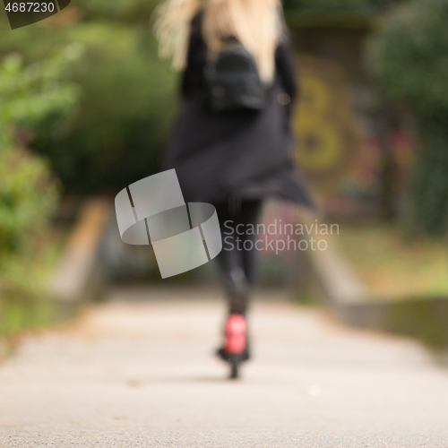 Image of Out of focus rear view of casual caucasian teenager riding urban electric scooter in city park during covid pandemic. Urban mobility concept.