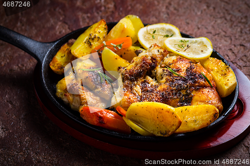 Image of Baked lemon chicken with potatoes, carrots and herbs served in pan