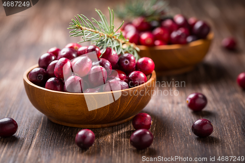 Image of Ripe organic cranberries in wooden bowl on wooden background