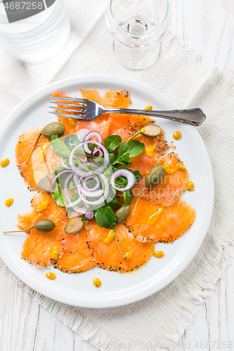 Image of Salmon carpaccio and arugula salad with onions and capers