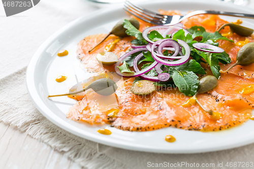 Image of Salmon carpaccio and arugula salad with onions and capers