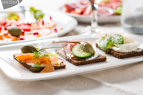 Image of Variation of healthy open sandwiches on Pumpernickel bread with vegetables, salmon, Prosciutto and appetizers