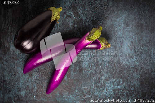 Image of Assortment of fresh aubergines on dark background