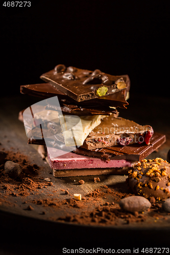 Image of Stack of assorted chocolate with cocoa and cocoa beans on black background