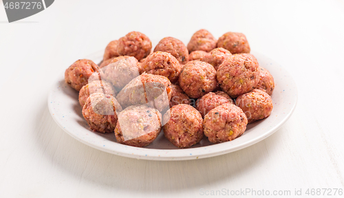 Image of Raw meatballs on plate and white background