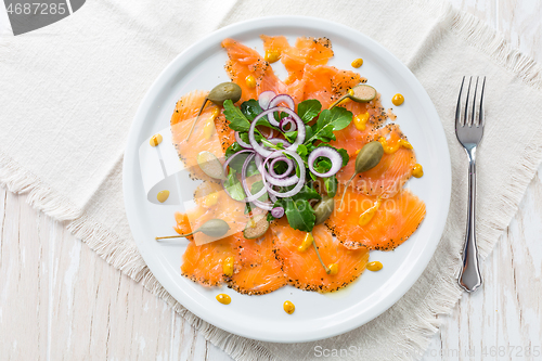 Image of Salmon carpaccio and arugula salad with onions and capers