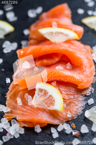 Image of Smoked salmon with lemon and sea salt on black background