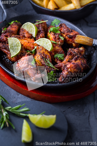 Image of Roasted chicken wings in barbecue sauce with lime and baked potatoes