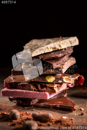 Image of Stack of assorted chocolate with cocoa and cocoa beans on black background