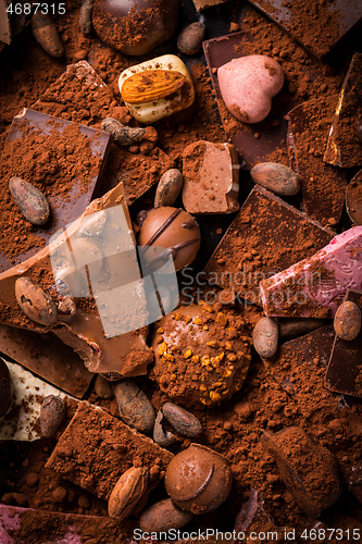 Image of Variation of chocolate and candy with cocoa and cocoa beans as background