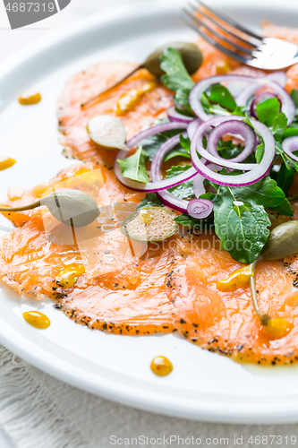 Image of Salmon carpaccio and arugula salad with onions and capers