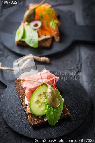 Image of Variation of healthy open sandwiches on Pumpernickel bread with vegetables, salmon, ham, herbs and soft cheese