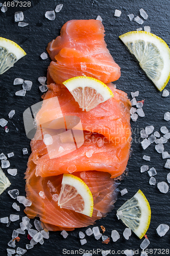 Image of Smoked salmon with lemon and sea salt on black background