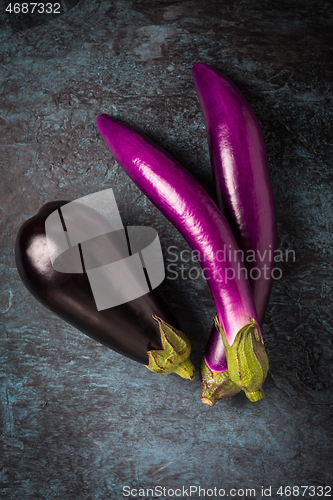 Image of Assortment of fresh aubergines on dark background