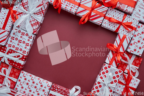 Image of Arranged Gifts boxes wrapped in colorful festive paper with on burgund background