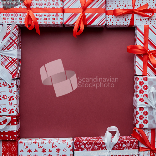 Image of Arranged Gifts boxes wrapped in colorful festive paper with on burgund background