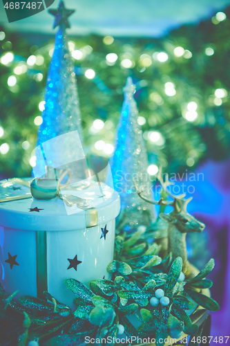 Image of Colorful christmas ornaments and decorations placed on small table with lights in background