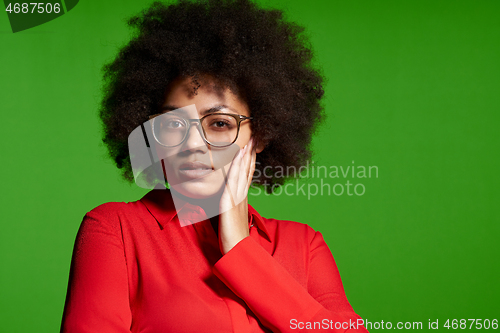 Image of Thinking young African-American girl in glasses and red shirt looking at camera