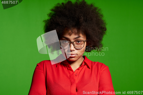 Image of Discontent serious young African-American girl in glasses and red shirt