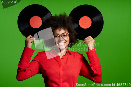 Image of Funny African-American girl in red shirt holding vinyl disc as ears