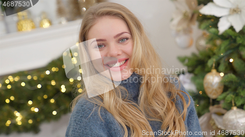 Image of Fashionable smiling woman wearing knitwear cozy sweater in front of christmas tree