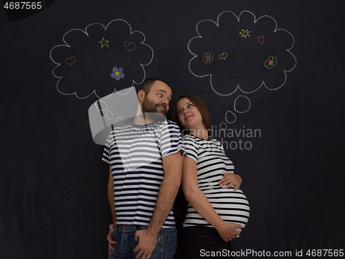 Image of pregnant couple posing against black chalk drawing board