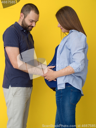 Image of pregnant couple  isolated over yellow background