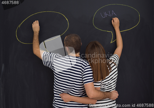 Image of pregnant couple writing on a black chalkboard