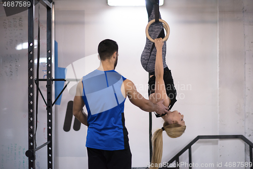 Image of woman working out with personal trainer on gymnastic rings