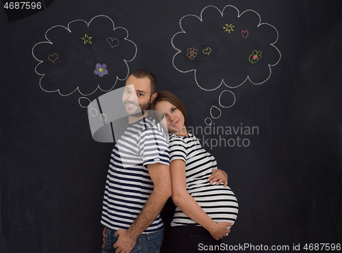 Image of pregnant couple posing against black chalk drawing board