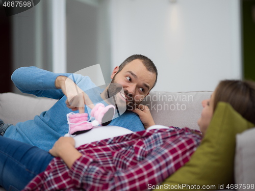 Image of young pregnant couple relaxing on sofa