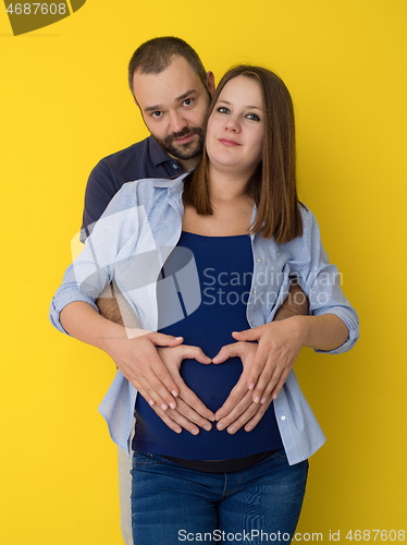 Image of pregnant couple  isolated over yellow background