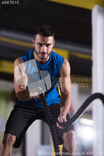 Image of athlete man doing battle ropes cross fitness exercise