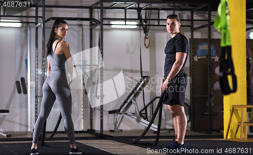 Image of sports couple doing battle ropes cross fitness exercise