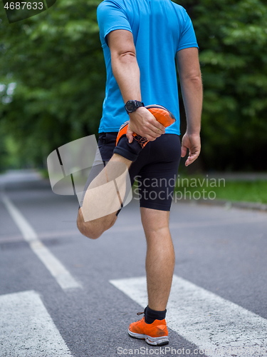 Image of male runner warming up and stretching before morning training